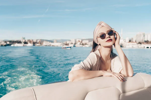 Una joven de lujo en gafas de sol disfruta relajarse en su yate blanco al sol —  Fotos de Stock