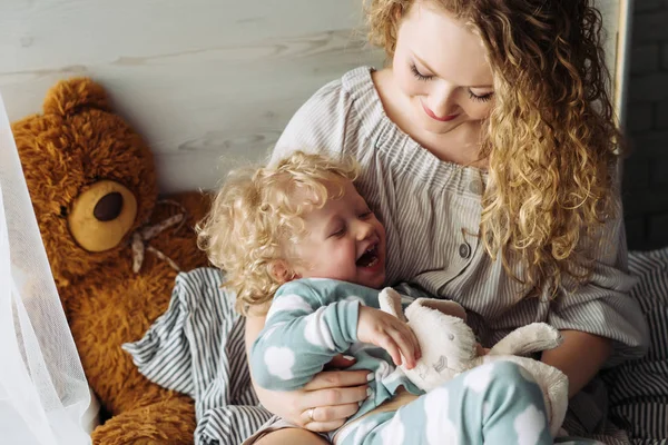 Feliz mamá rizada jugando con su pequeño hijo, riendo, familia amistosa — Foto de Stock