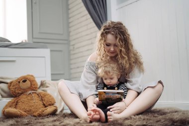 kıvırcık genç anne küçük oğlu okumak, birlikte vakit geçirmek için öğretir