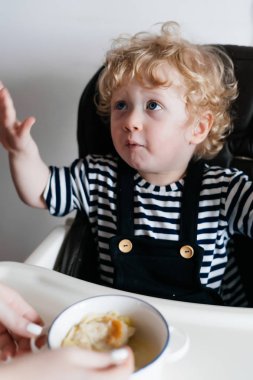 lezzetli bir yararlı tahıl yemek mutfakta bir çocuk sandalyede oturan küçük kıvırcık erkek bebek