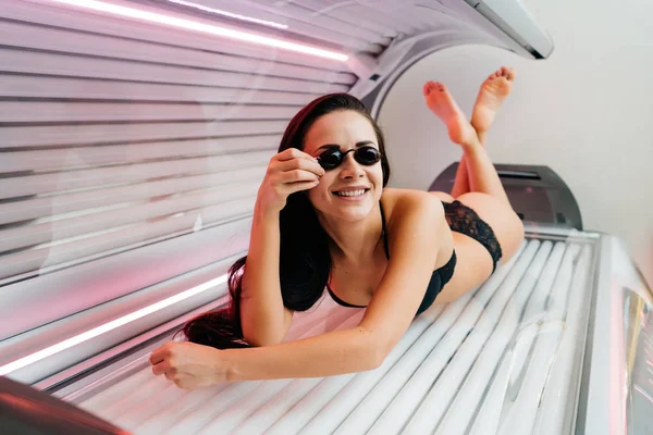 Λεπτός πολυτελείας κορίτσι σε ένα μαγιό ηλιοθεραπεία σε μια ξαπλώστρα, φορώντας γυαλιά και χαμογελαστός — Φωτογραφία Αρχείου