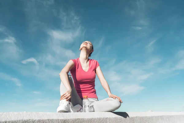 Chica joven delgada en ropa deportiva descansando después del ejercicio al aire libre — Foto de Stock