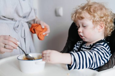 Aile yemeği, bakmakta genç bir anne küçük kıvırcık oğlu yararlı püresi ile beslenir.