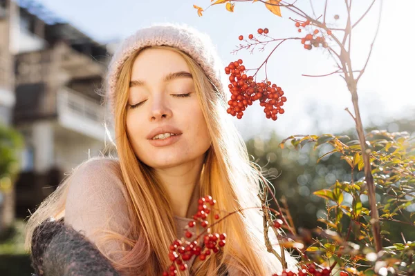 Glada blond flicka i hatt går igenom vårträdgård, åtnjuter sol och leenden — Stockfoto