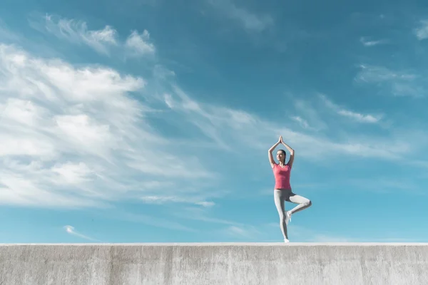 Aktivní mladá dívka zabývající se jógu pod modrou oblohou, protahuje svaly, je zklidněném — Stock fotografie