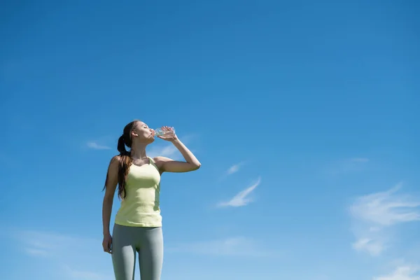 Sportovní mladá dívka pije vodu po těžké dlouhé cvičení venku na teplý jarní den — Stock fotografie