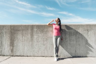 ince atletik genç kız sonra bir zor egzersiz açık havada, içme suyu, susuzluğunu güç kazanıyor