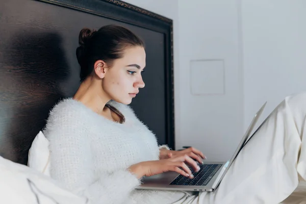 Enfoque chica joven sentada en la cama y con entusiasmo viendo series de televisión en el ordenador portátil — Foto de Stock