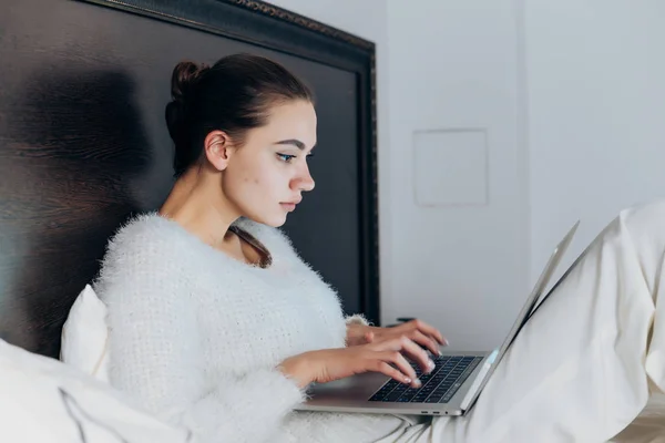 Enfoque chica joven sentada en la cama y con entusiasmo viendo series de televisión en el ordenador portátil —  Fotos de Stock