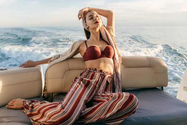 Una mujer rica y lujosa en ropa de verano con estilo se relaja en su yate, navega en las islas del Caribe —  Fotos de Stock