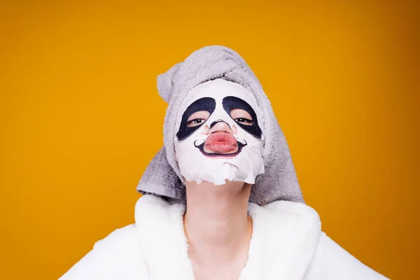 Grappig meisje met een handdoek op haar hoofd kwam uit de douche, gezichtsmasker met een gezicht van de panda — Stockfoto