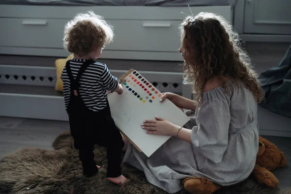 Friendly young family, curly mother draws with her little son, spend time together — Stock Photo, Image