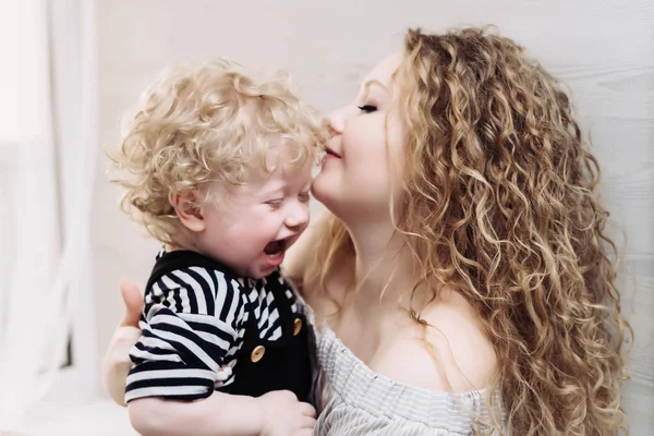 Happy friendly family, curly mother holding her young son in her arms, laughing — Stock Photo, Image