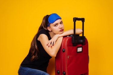 yorgun bir genç kız uçağı için uzun süre beklemek büyük bir kırmızı çanta, bir geziye gidiyor