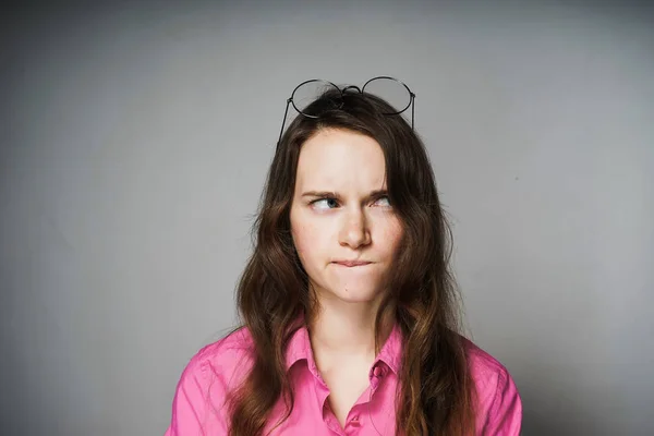 Jovem mulher em uma camisa rosa e óculos pensa sobre o trabalho — Fotografia de Stock