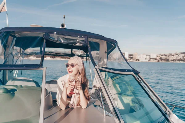 Una chica atractiva de lujo en gafas de sol nada en su yate blanco a las islas, se ríe —  Fotos de Stock