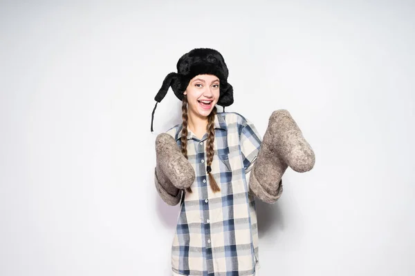 Funny Russian girl in a warm fur hat rejoices in winter, holds gray felt boots and laughs — Stock Photo, Image