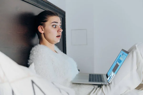 Genç kız yatakta akşamları oturup onu laptop korku filmi izlerken korkuttu — Stok fotoğraf