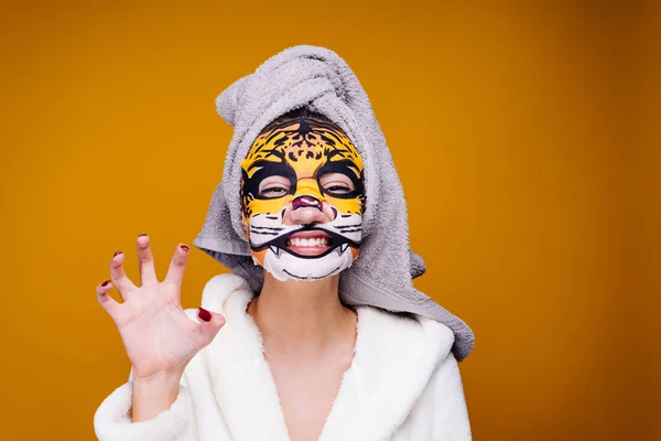 Legrační mladá dívka s ručníkem na její hlavu vrčí jako zvíře, na její tváři masku s tváří leopard — Stock fotografie