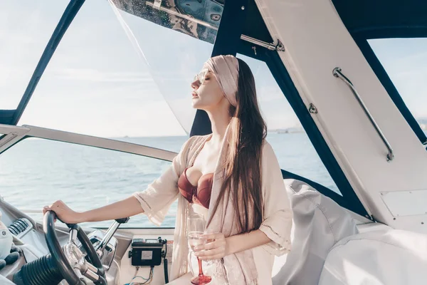 Beautiful attractive woman enjoys a rich life and leisure, runs her white yacht and drinks champagne — Stock Photo, Image