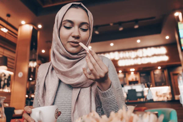 Schöne arabische Mädchen mit einem Kopftuch auf dem Kopf speist in einem gemütlichen orientalischen Café und ruht — Stockfoto