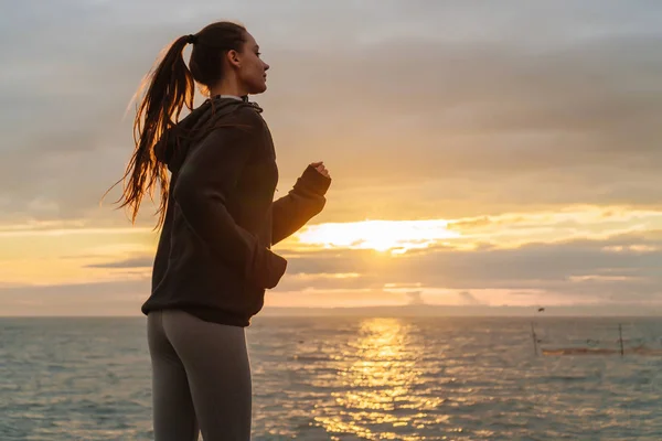 Fiduciosa ragazza sportiva corre intorno al mare al tramonto, treni prima delle competizioni — Foto Stock