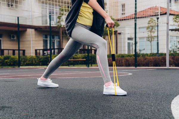 Actief slank meisje kneden voor opleiding op een sportveld buiten, swings beenspieren — Stockfoto