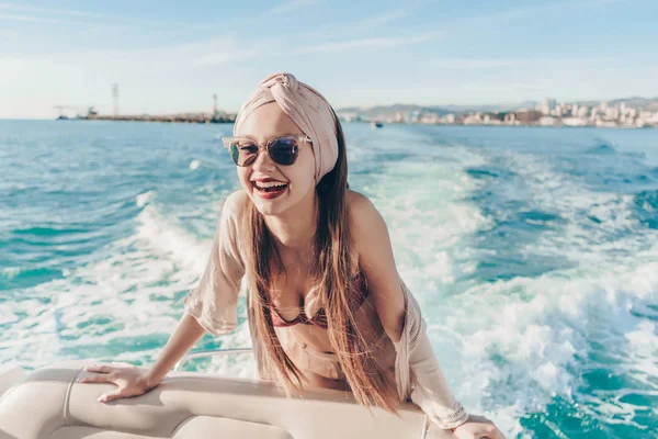 An attractive girl in sunglasses swims on her white yacht on the eagle, laughs, enjoys sea voyage — Stock Photo, Image