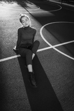 poz, spor alanında yere oturup şık kız modeli