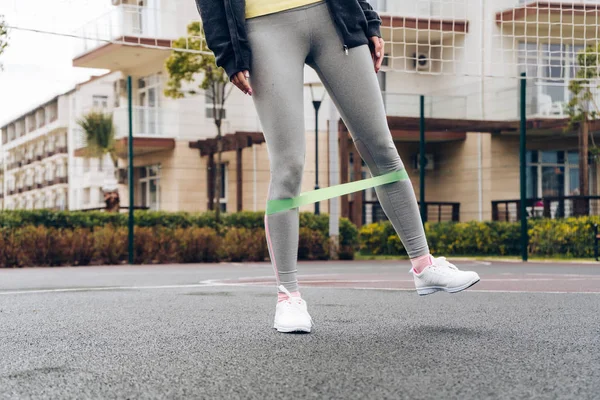 athletic young girl exercising on an outdoor sports field, swings leg muscles