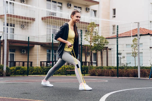 Confiado fuerte chica entrena en el campo de deportes, amasa los músculos de las piernas — Foto de Stock