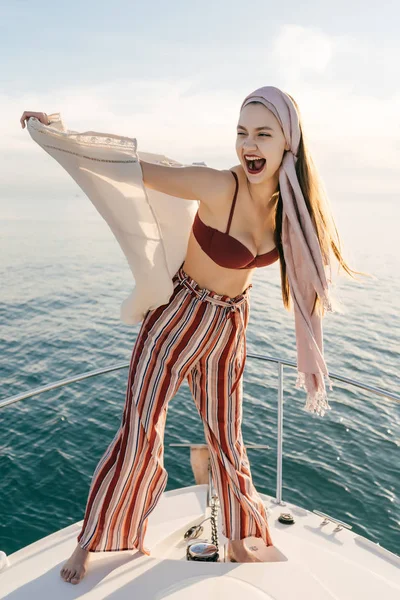 Riéndose chica alegre en ropa de verano con estilo descansa en su yate blanco, disfruta de una vida rica —  Fotos de Stock