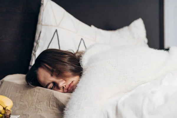 Schläfriges junges Mädchen im Schlafanzug liegt im Bett, schläft, frühmorgens, kann Wecker nicht hören — Stockfoto