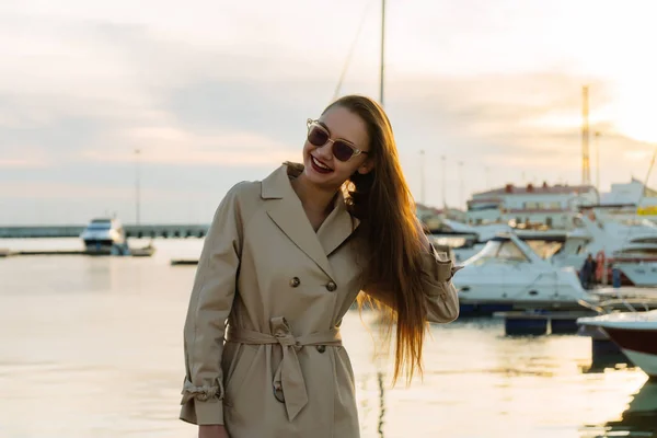 Luxueuse fille aux cheveux longs en lunettes de soleil posant dans le port de mer, riant — Photo