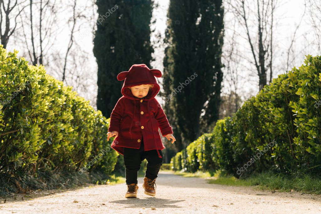 cute little baby boy in a funny suit walks along the green park