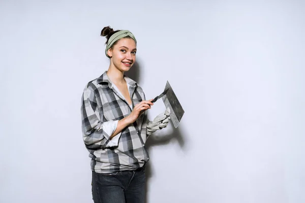 Mooi jong meisje in werkende shirt doen van reparaties in appartement, bedrijf spatel in handen en glimlachen — Stockfoto