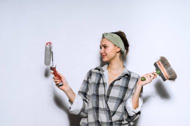 güzel genç kız ressam bir fırça ve bir silindir duvarları ve can boyama için tercih holding