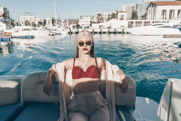 一位戴着墨镜的美女坐在阳光下的白色游艇上, 在海上航行 — 图库照片
