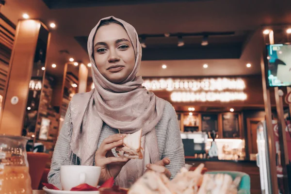 Szép Arab lány hidzsáb ül egy hangulatos keleti kávézóban ebédel és mosolyog — Stock Fotó