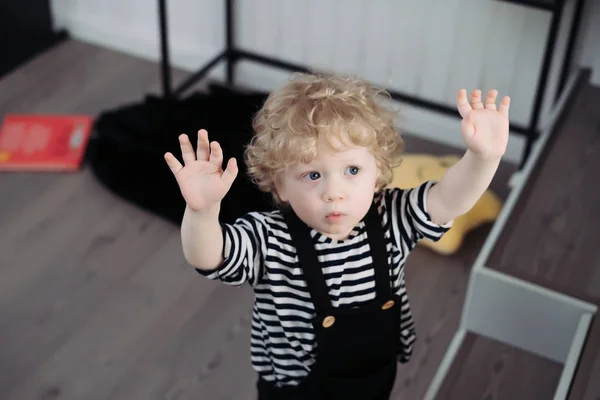 Кучерявий маленький хлопчик у милому костюмі підняв руки вгору — стокове фото