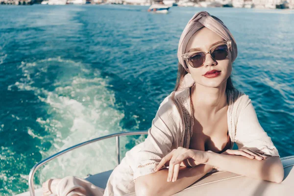 Napszemüveg-vonzó fiatal nő ül ő fehér jacht, pózol, élvezi a nyaralás a tengerparton — Stock Fotó