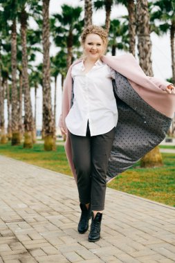 mutlu genç kadın parkta yürüyüş şık pembe ceket gülümseyen