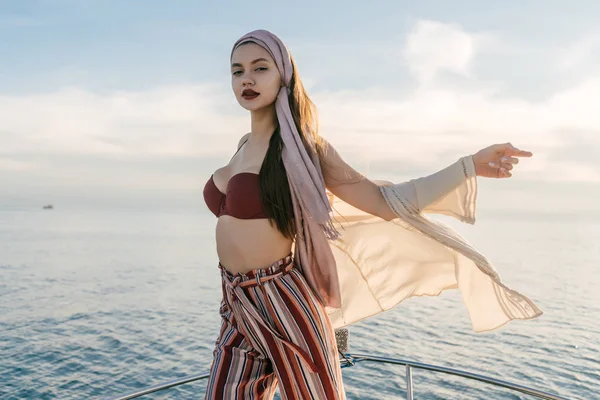 A luxurious stylish girl stands on her white yacht, the wind blows, poses — Stock Photo, Image