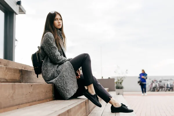 Dark haired city girl posing outdoors in trendy gray coat, street style — Stock Photo, Image