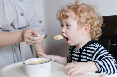 şefkatli anne beslemeleri genç çocuğu evlat yararlı püresi ile bir kaşık ile bir aile Kahvaltı