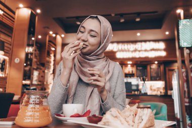sevimli genç Arap kız hijab rahat oryantal kafede, lezzetli yiyecek Öğle Yemeği