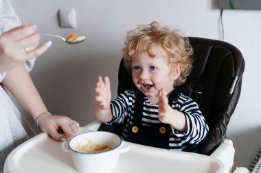 yararlı bir Mısır gevreği yemek sandalyesi mutfakta oturup küçük oğlu gülüyor