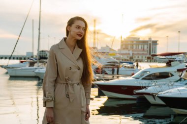 uzun saçlı sevimli kız bej bir palto, liman, bir denizde gitmek istiyor bir yatta yolculuk