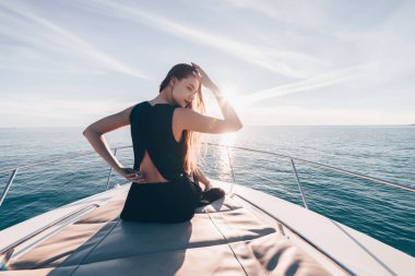 uzun saçlı zengin kadın siyah yaz giysileri güneş bir yatta oturur, Karayip Denizi üzerinde yelken