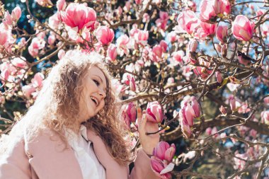 zarif kadın gülüyor parkta, sıcak bahar kokulu Manolya sahiptir